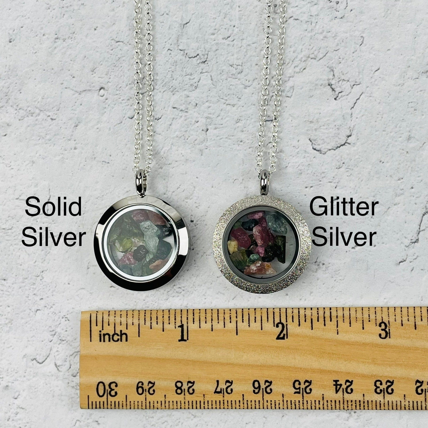 pendant available in solid silver color or glitter silver. next to a ruler for size reference 