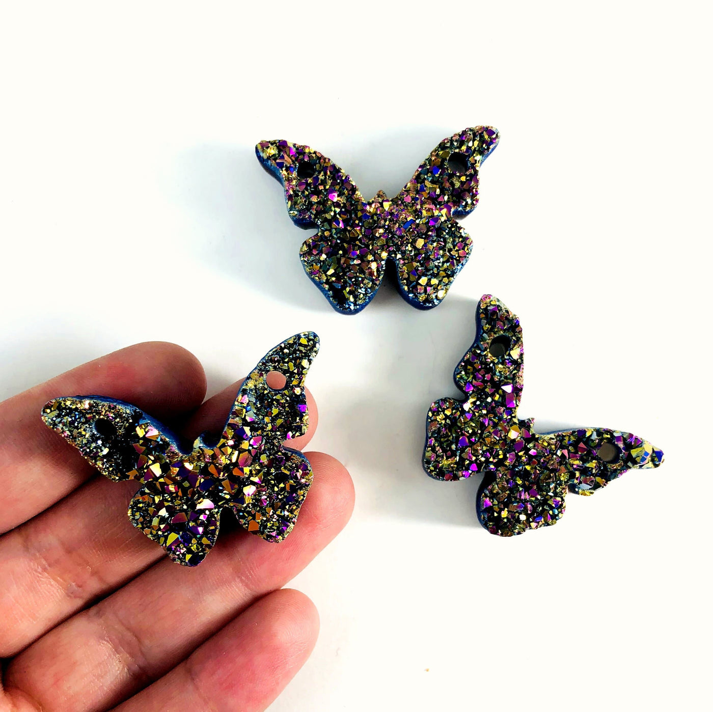 hand holding up butterfly druzy pendant with others in the background