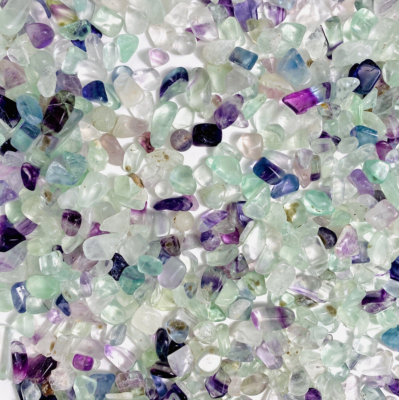 close up of fluorite chips in green purple and blue on a white background