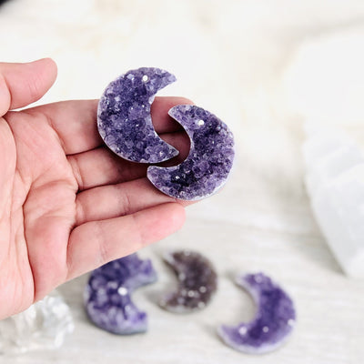 two amethyst moons in a woman's hand.