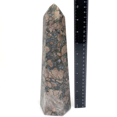 Rhyolite tower is being displayed in a completely white back ground. The item is placed next to a black ruler for size reference. 