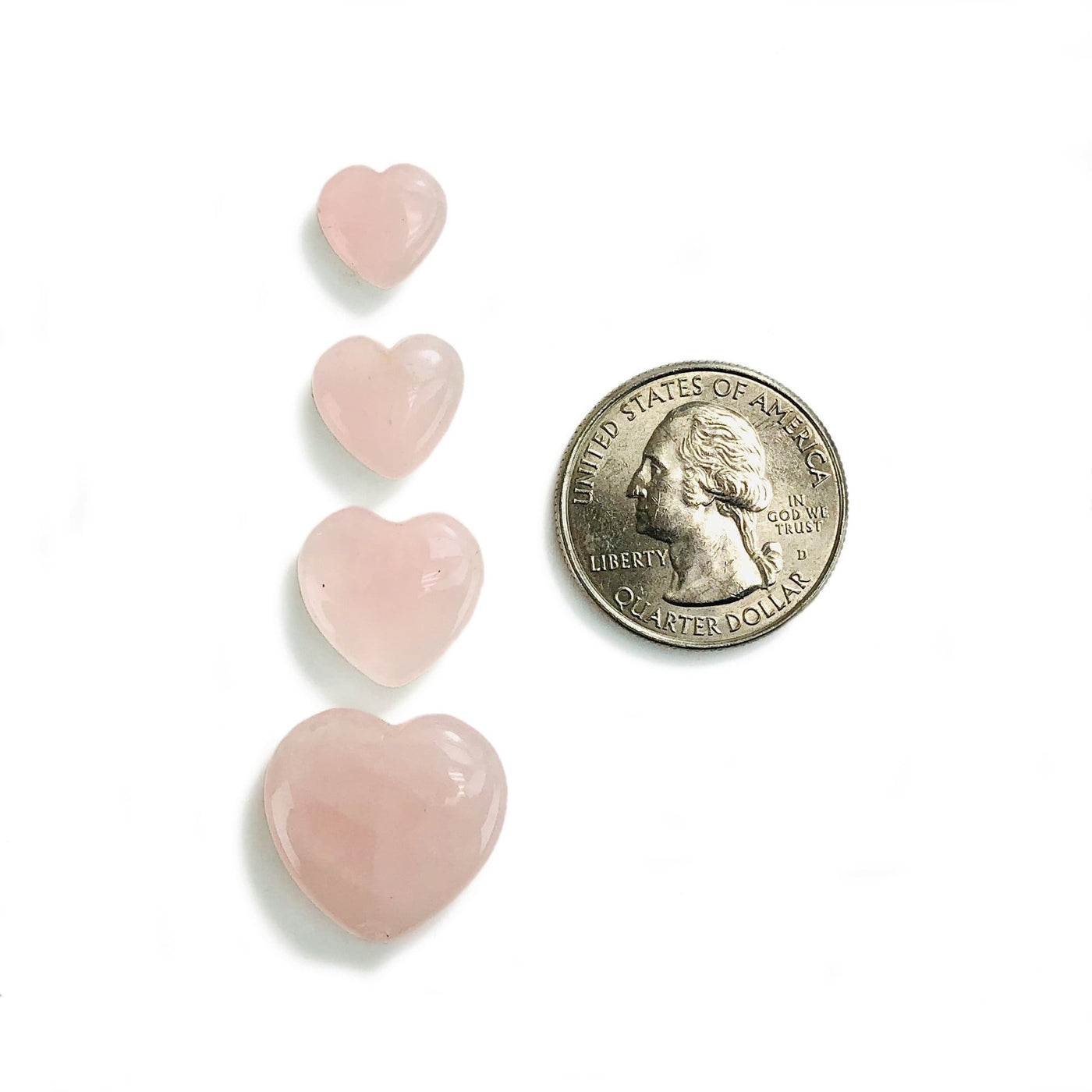 4 Rose Quartz Hearts next to a quarter for size reference on white background