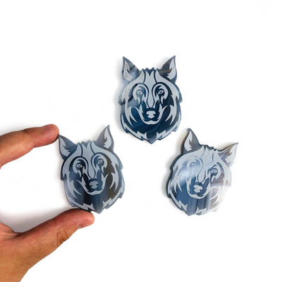 fingers holding Gemstone Wolf Slices with 2 others on white background