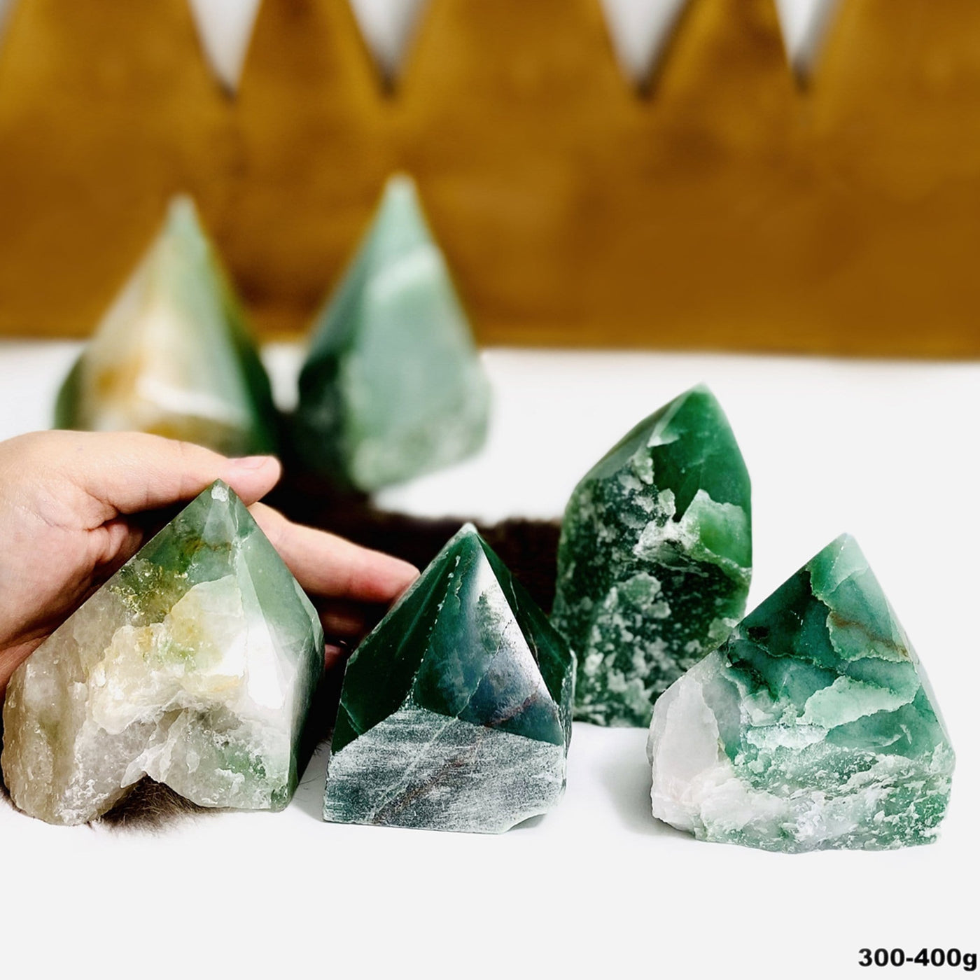 Assortment of green and white quartz semi polished points.  They are polished on top and rough along the sides.  They have a cut base so they can stand on their own.