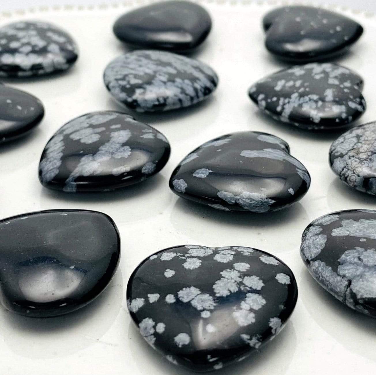 angled view of many snowflake obsidian hearts for thickness