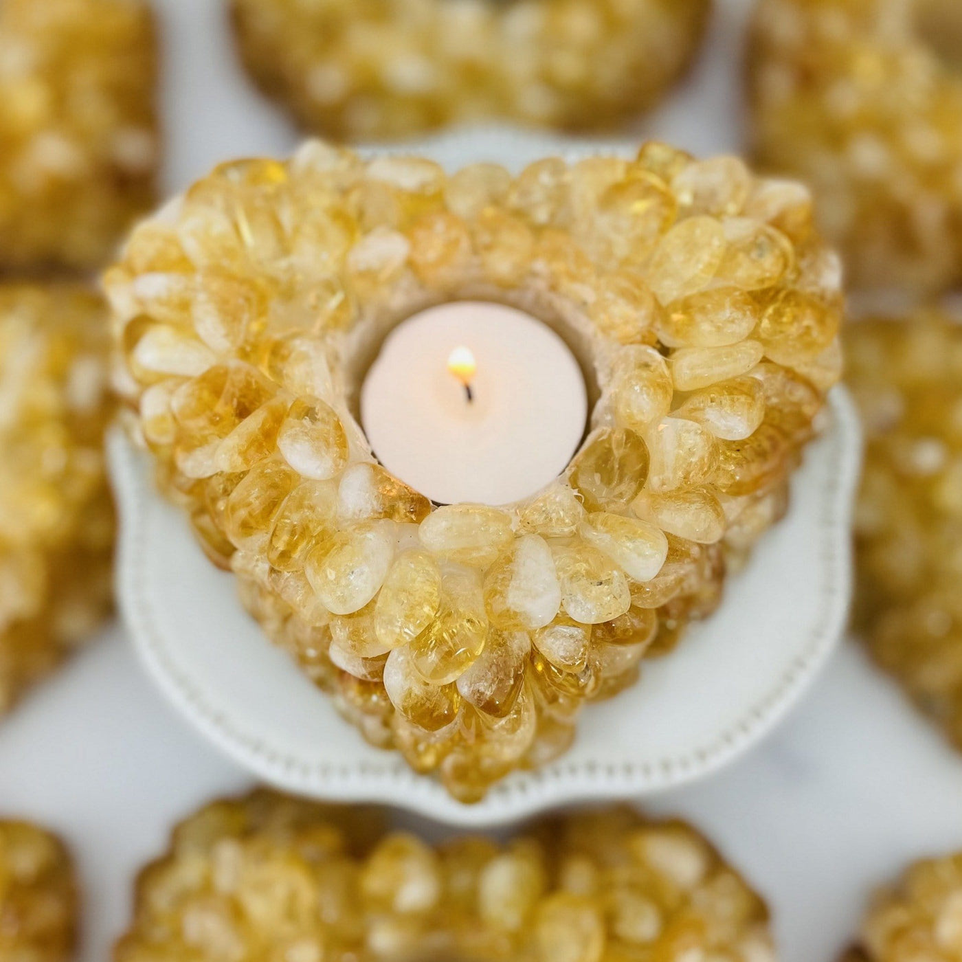 Citrine Tumbled stone Heart Candle Holder shown from overtop with a candle with others in the background