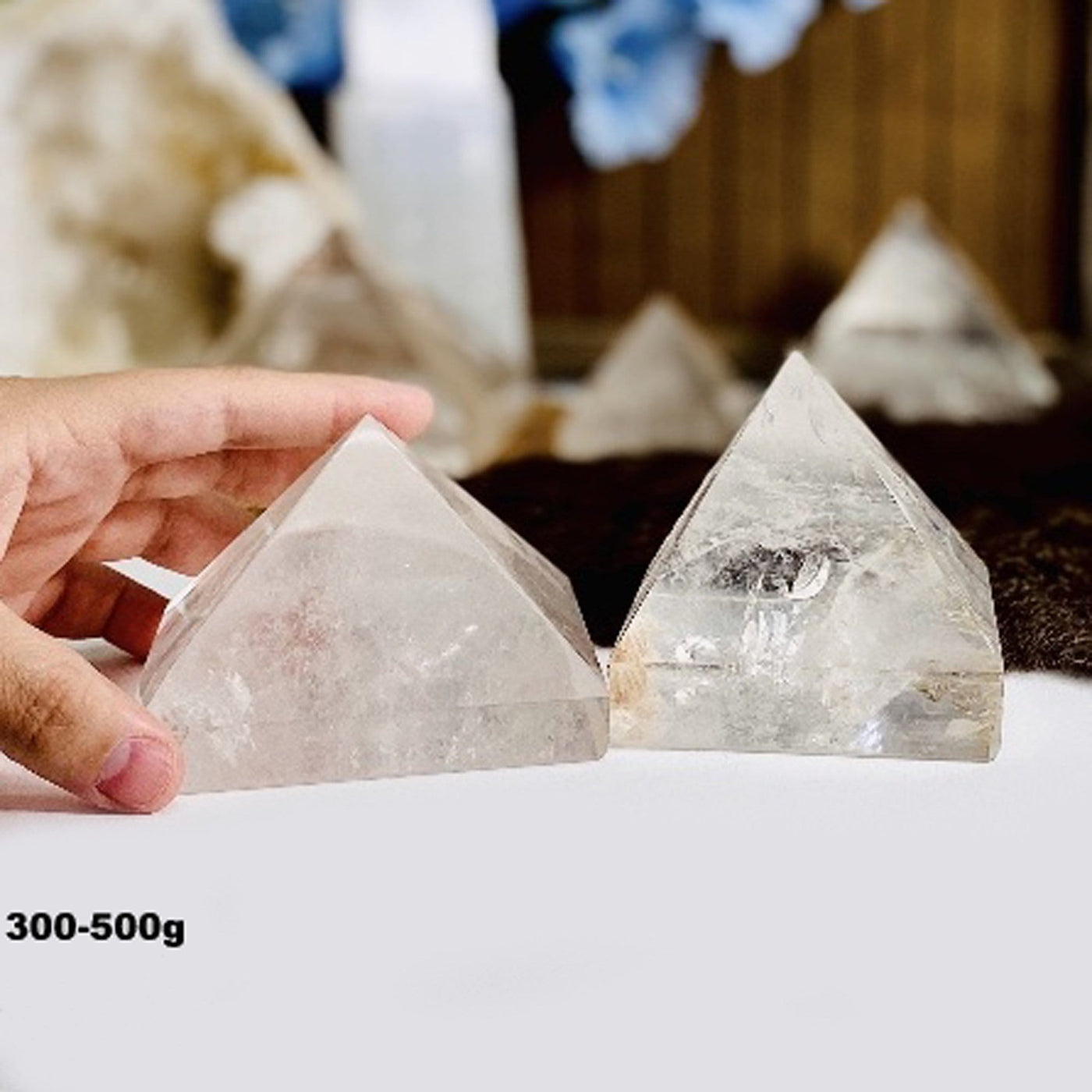 hand holding 300-500g Crystal Quartz Pyramid with others in the background