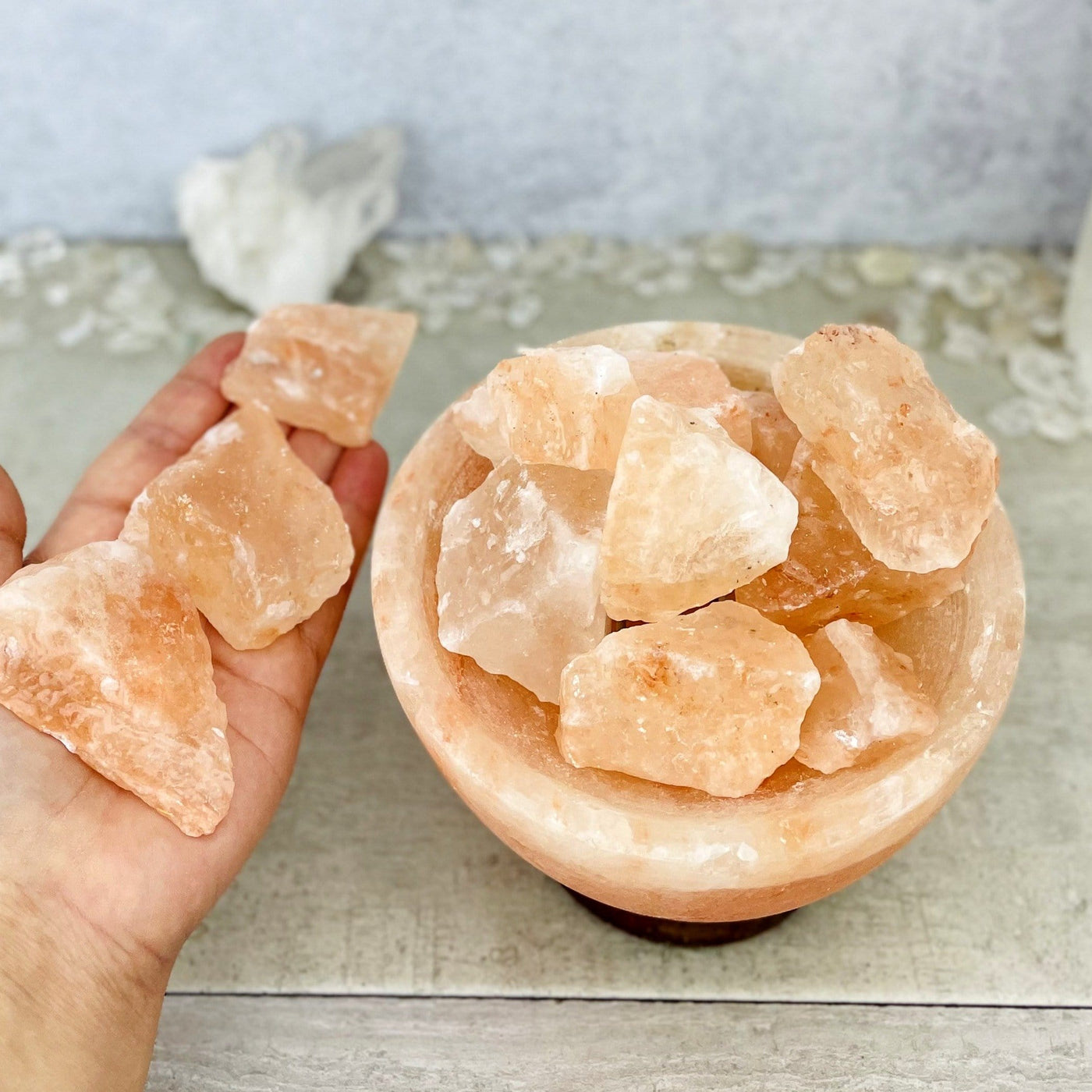 hand holding up Himalayan salt chunks next to Himalayan Salt Lamp