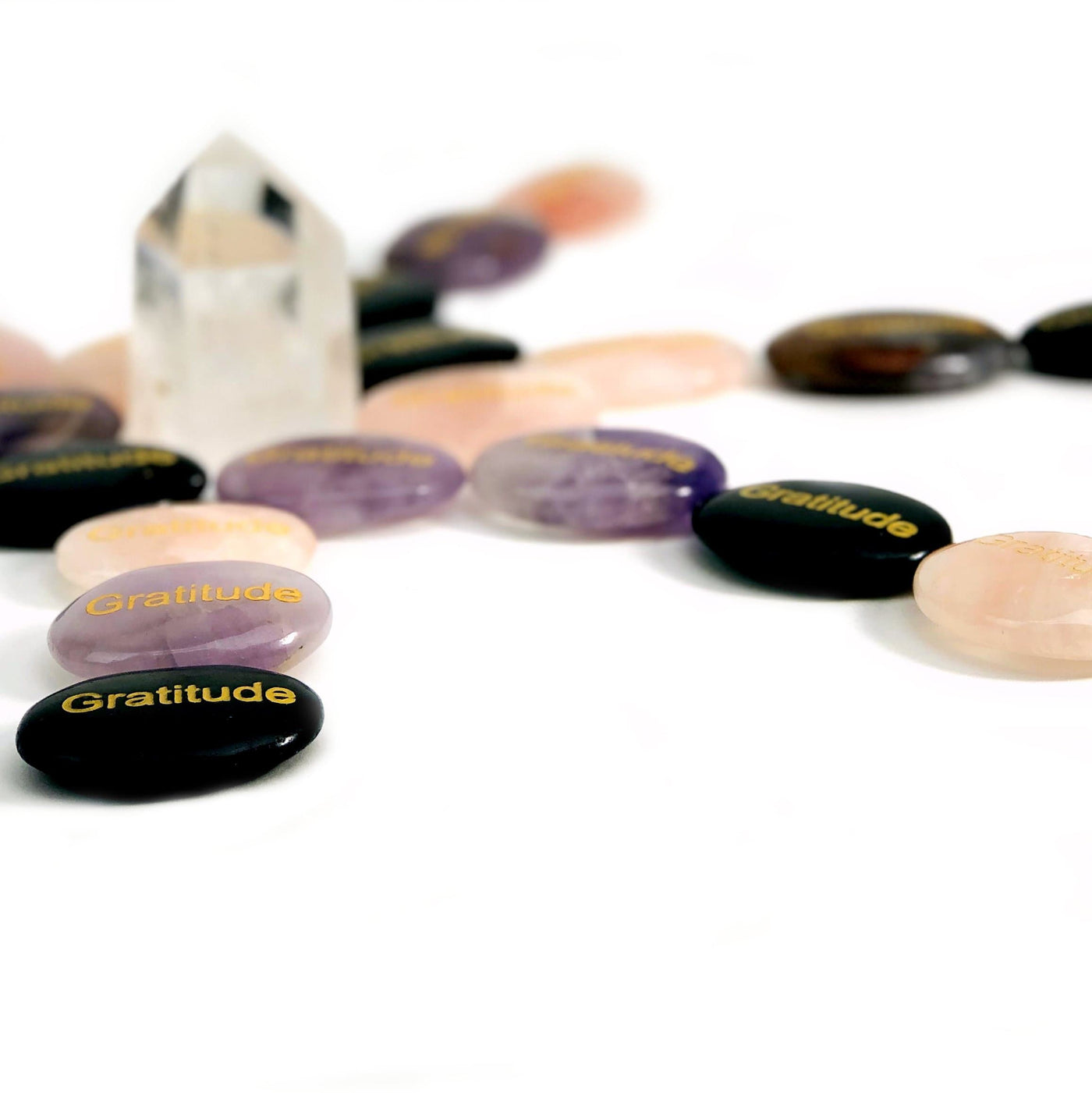 Various "Gratitude" Pocket Palm Stones laid out on a white surface.