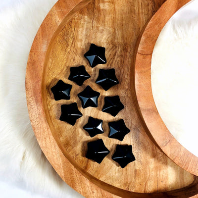 10 Black Obsidian Puffy Star Cabochon Gemstones displayed on a wooden moon shaped tray.