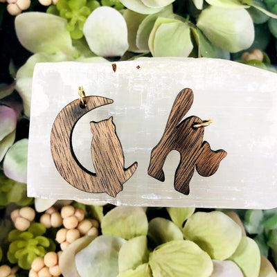 2 wooden cat pendants with decorations in the background