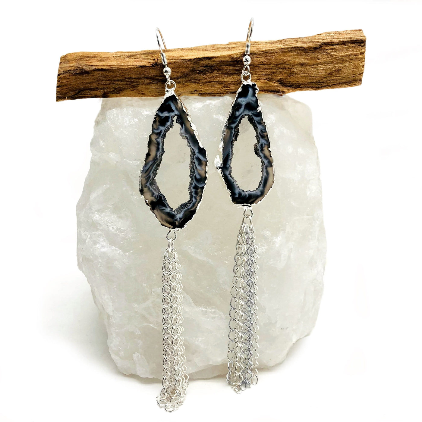 One pair of silver toned Agate Geode Slice Dangle Earrings displayed on a crystal with a white background.