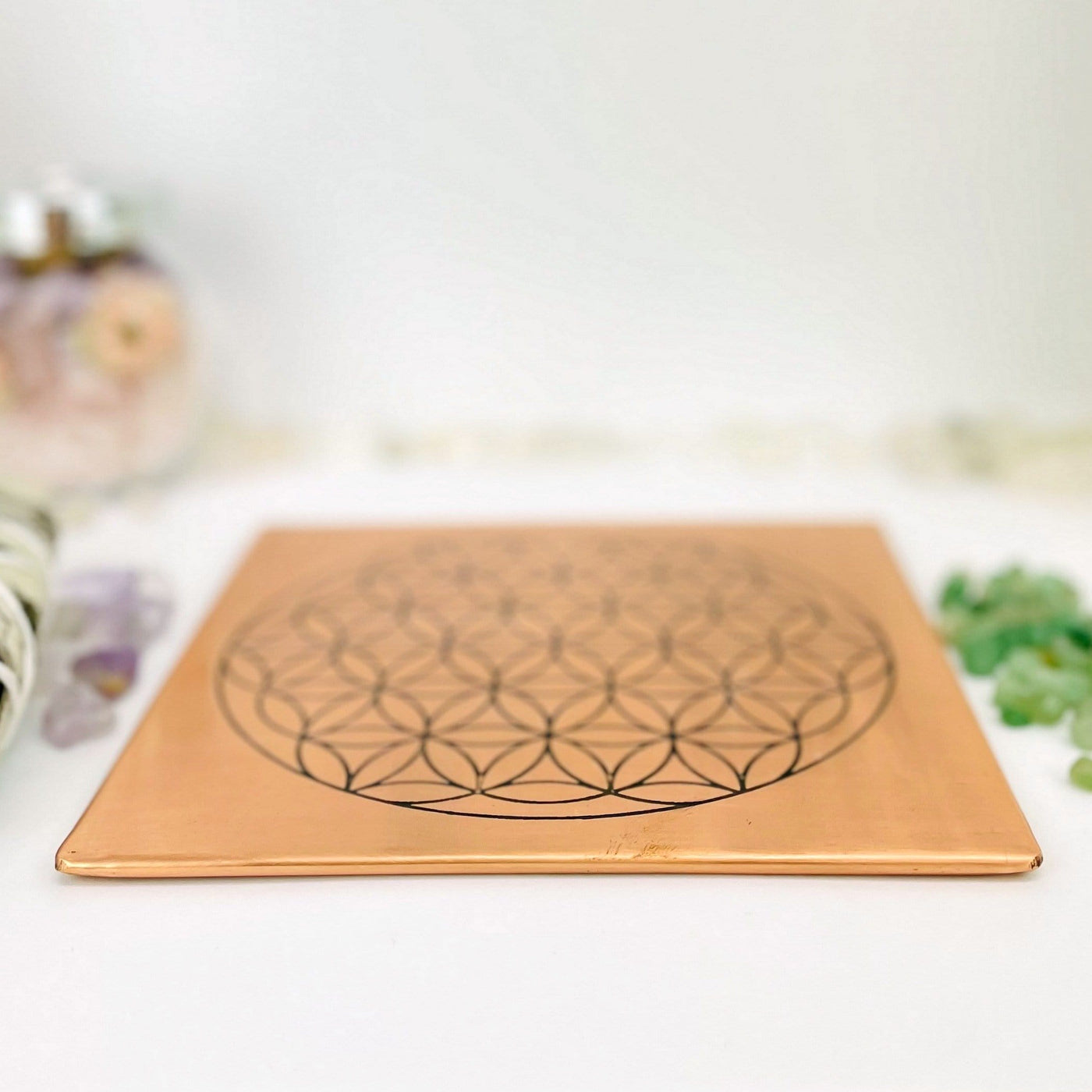 close up of copper square flat plate with a flower of life grid in black on it 