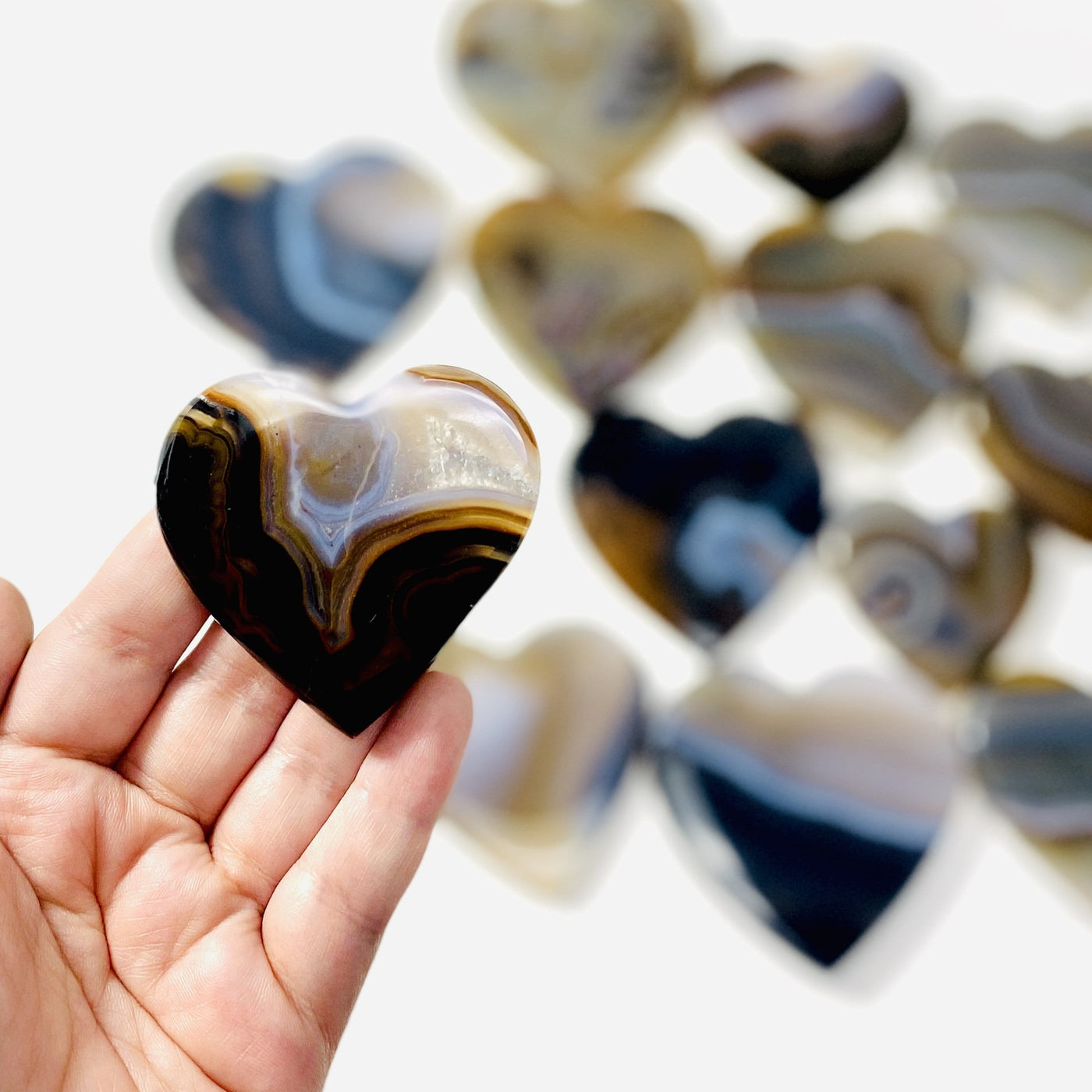 Agate Natural Heart Slice held in hand while others remain out of focus