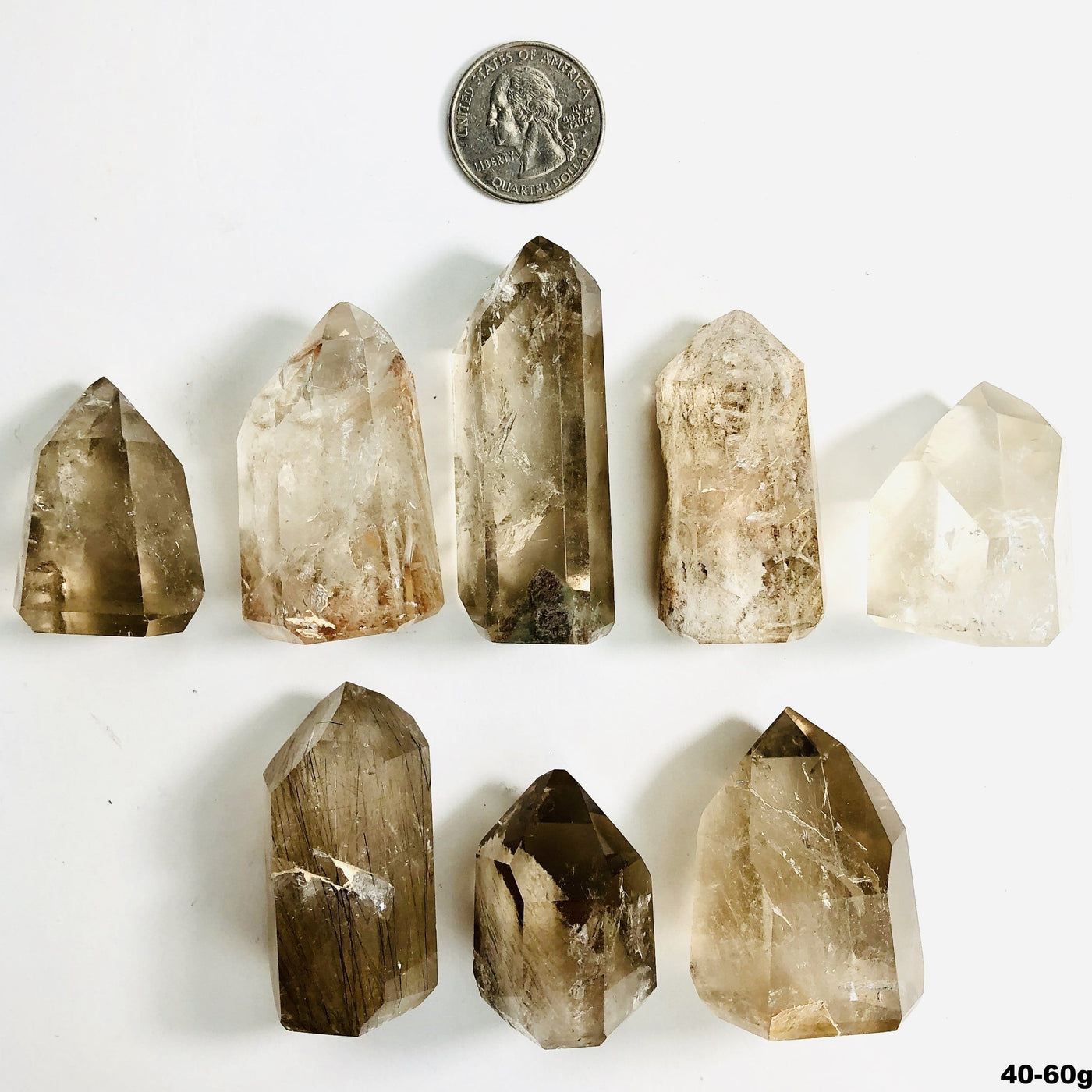 8 40-60g crystal points with inclusions next to a quarter for size reference on white background