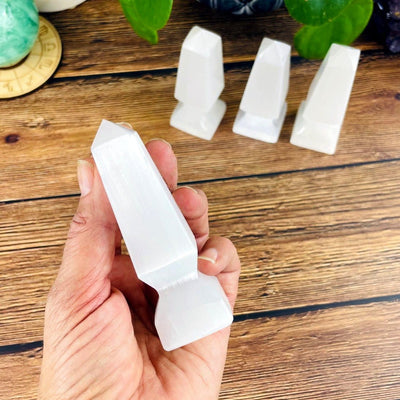 selenite spear tip in hand for size reference with others in background display
