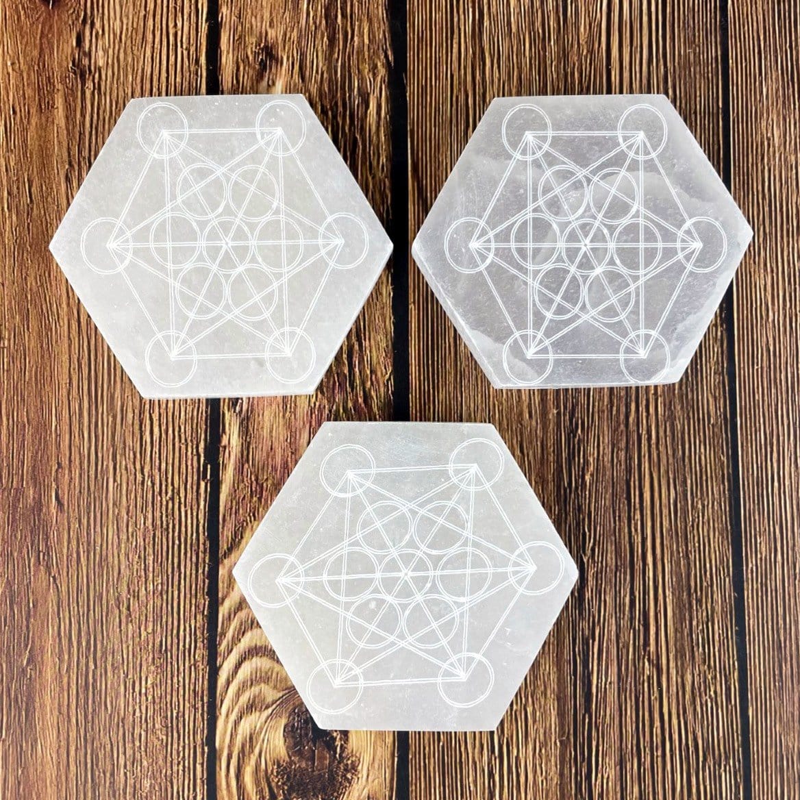 overhead view of three selenite hexagons engraved with metatron symbol for engraving details and possible variations 