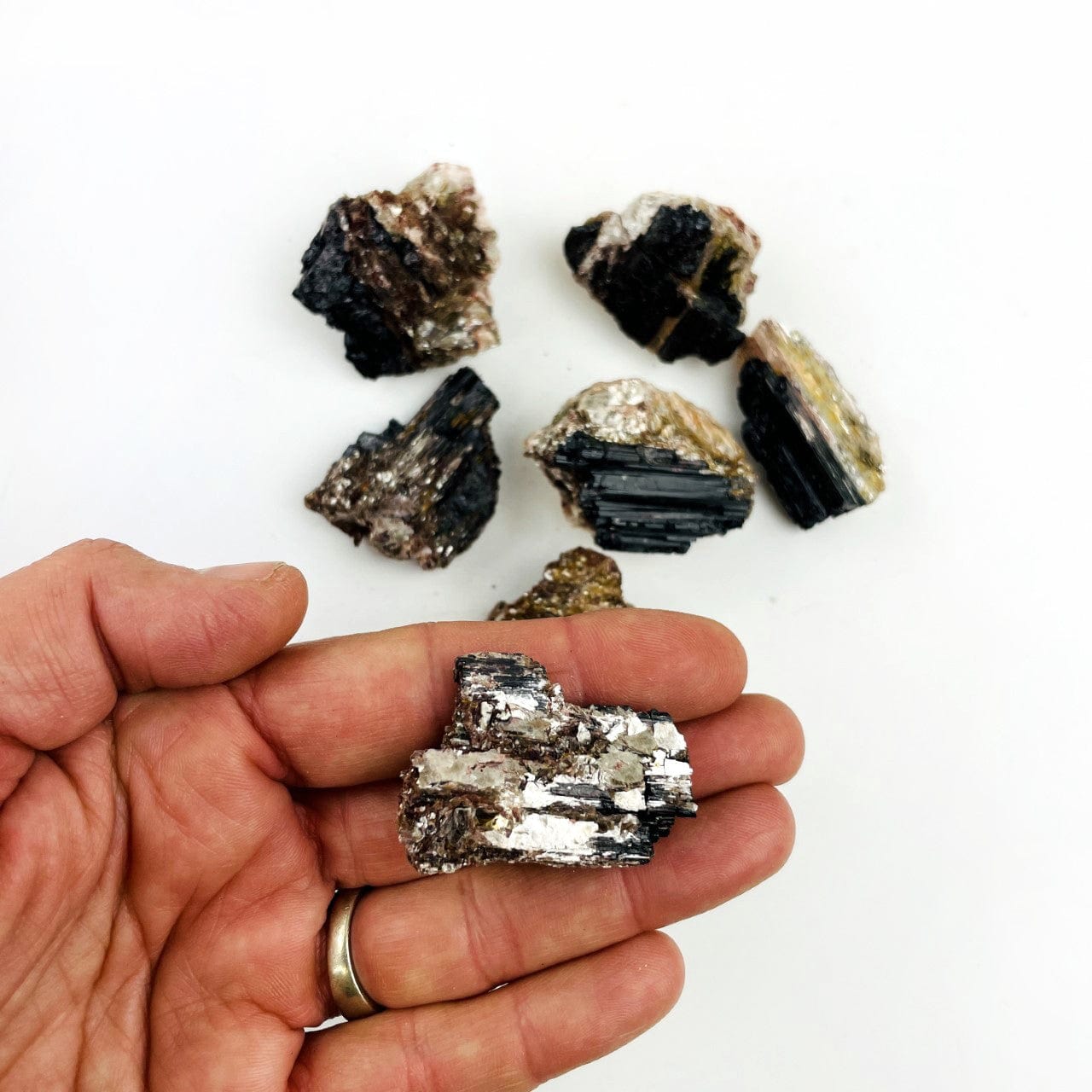 Tourmaline With Mica  on a table and one in the hand for size reference