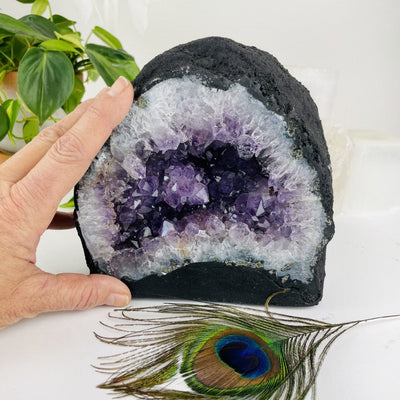hand next to Amethyst Cathedral Geode Crystal with decorations