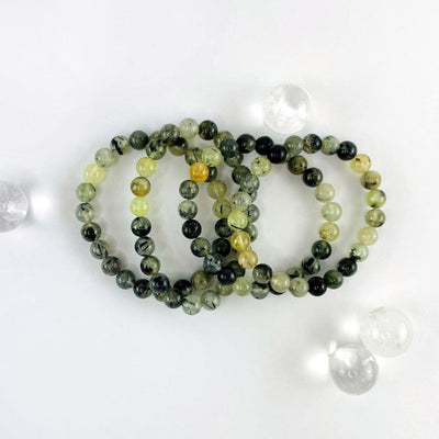 close up of the prehnite bracelets to show the green and some black details 