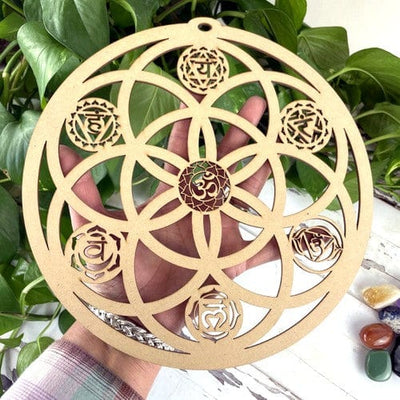 round wooden seed of life grid with chakras in hand for size reference 