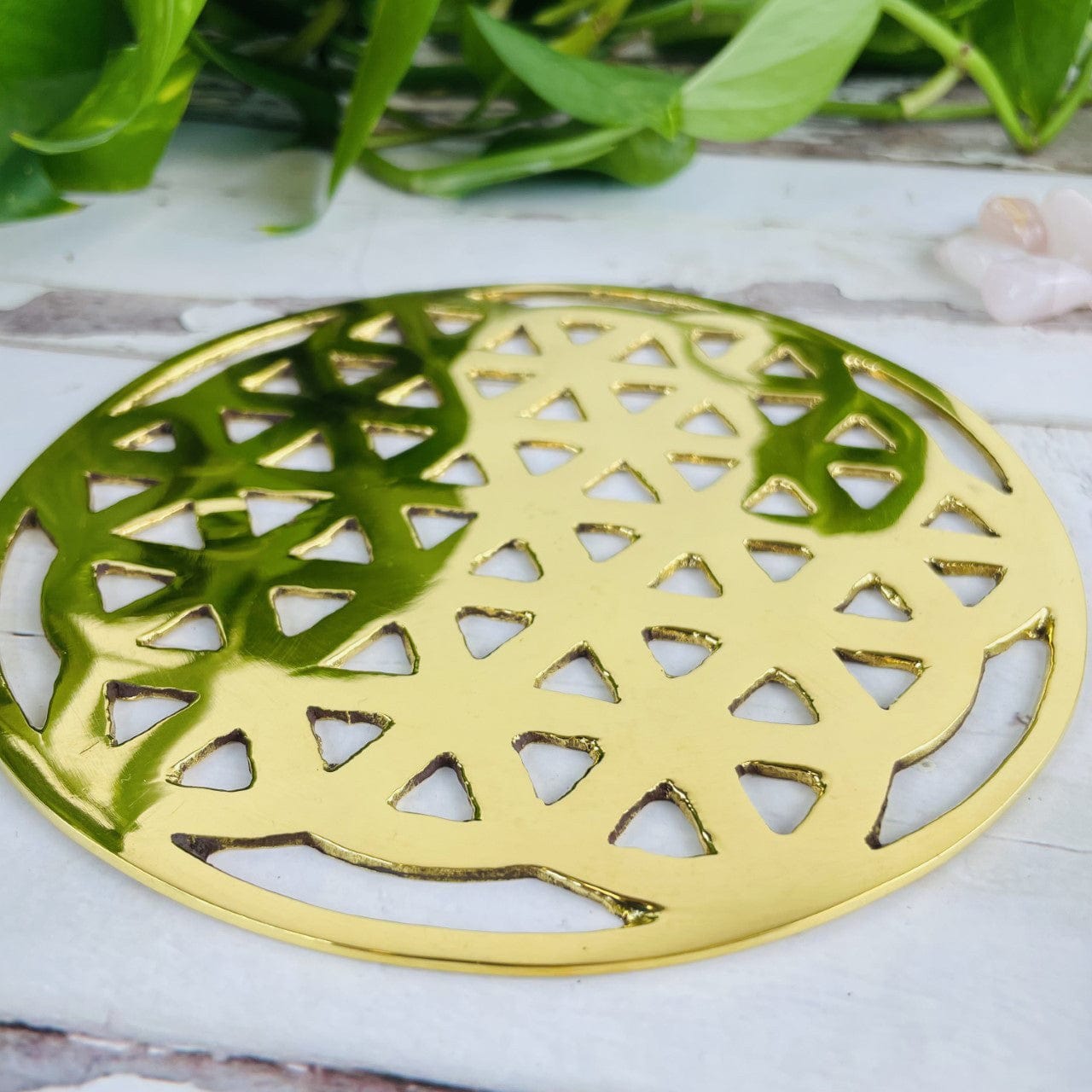 angled shot of brass flower of life grid with decorations in the background