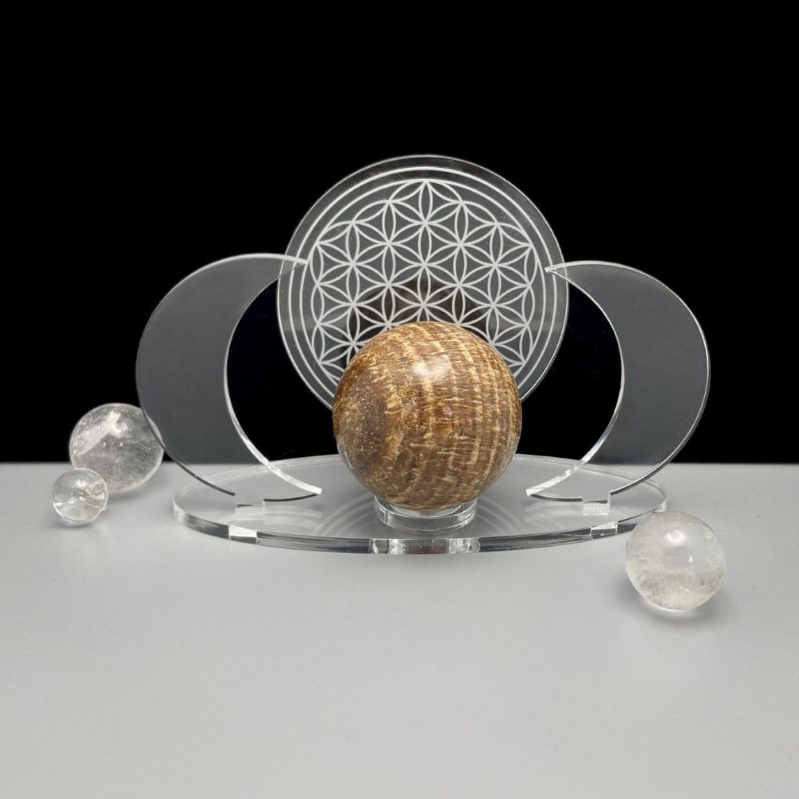 A front angle of an Acrylic Sphere Holder Crescent Moons - Flower of Life holding a sphere surrounded with a few smaller spheres.