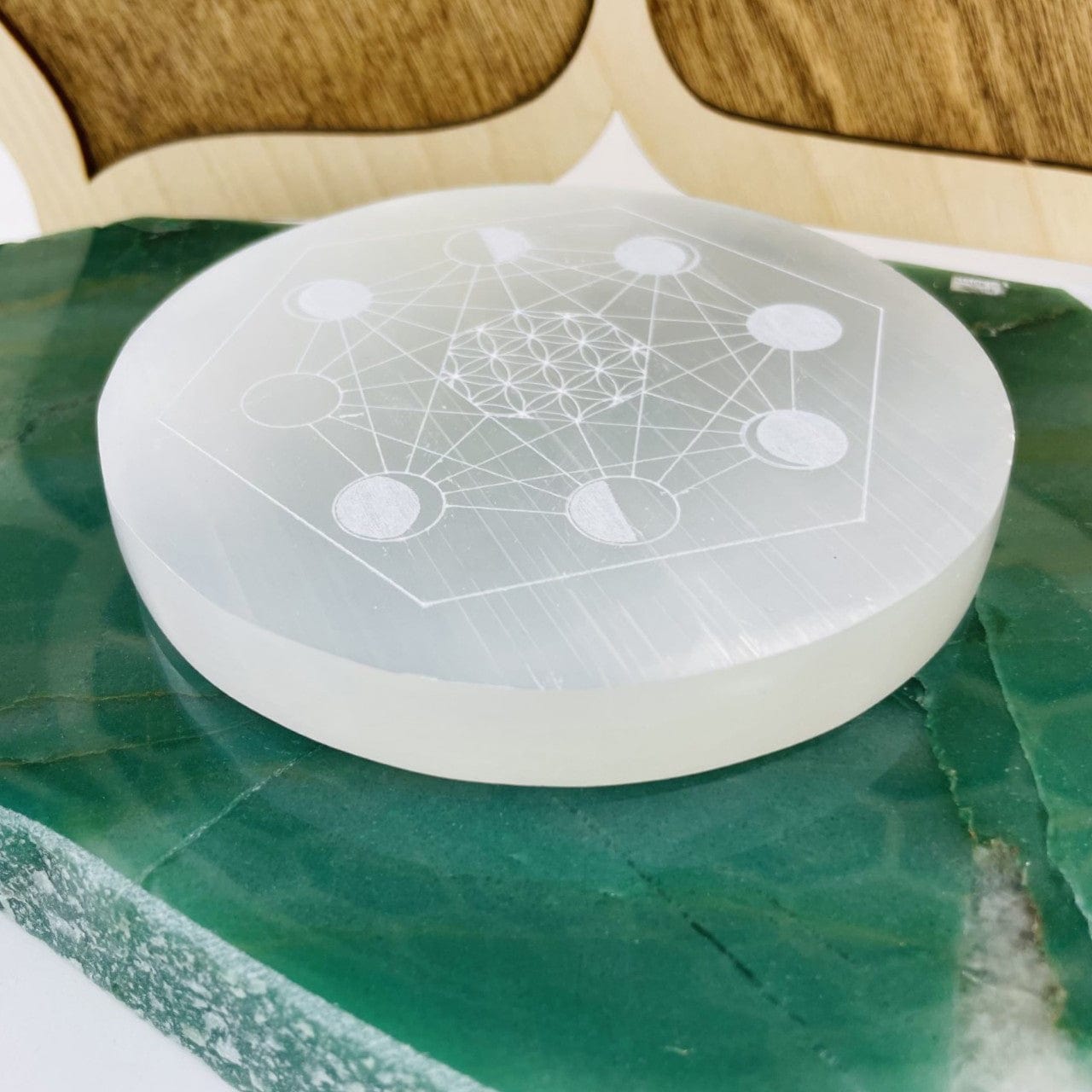 angled view of selenite moon phase engraved charging plate for thickness
