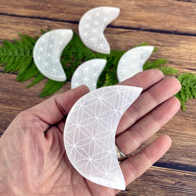 selenite moon with flower of life grid in a womans hand