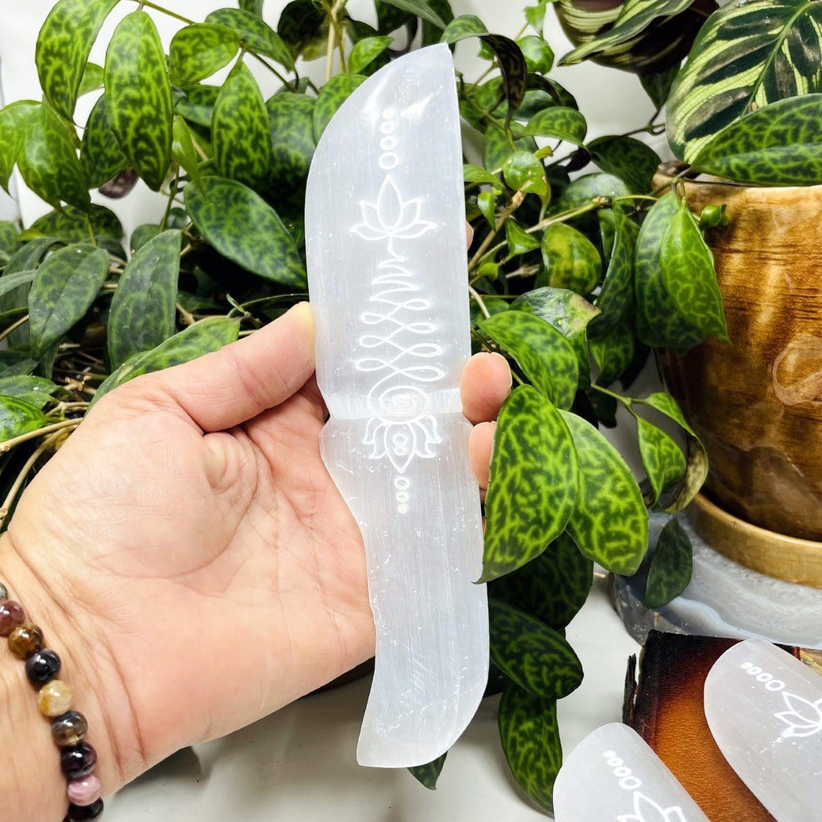 selenite knife with unalome engraving in hand for size reference