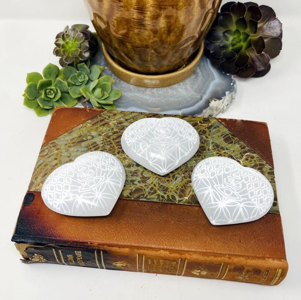 three selenite stone hearts with eye engraving on display