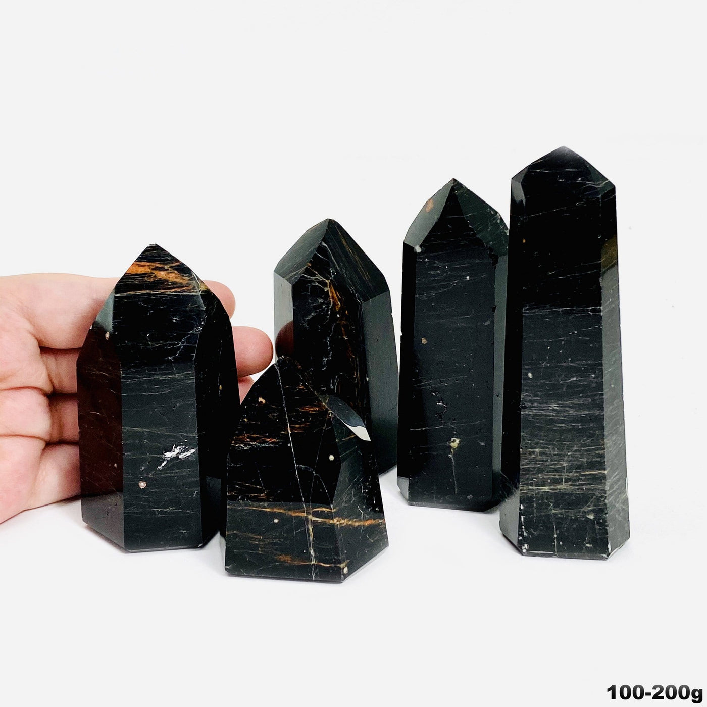 hand behind 100-200g black tourmaline with red iron polished points
