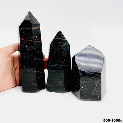 hand behind 500-1000g black tourmaline with red iron polished points