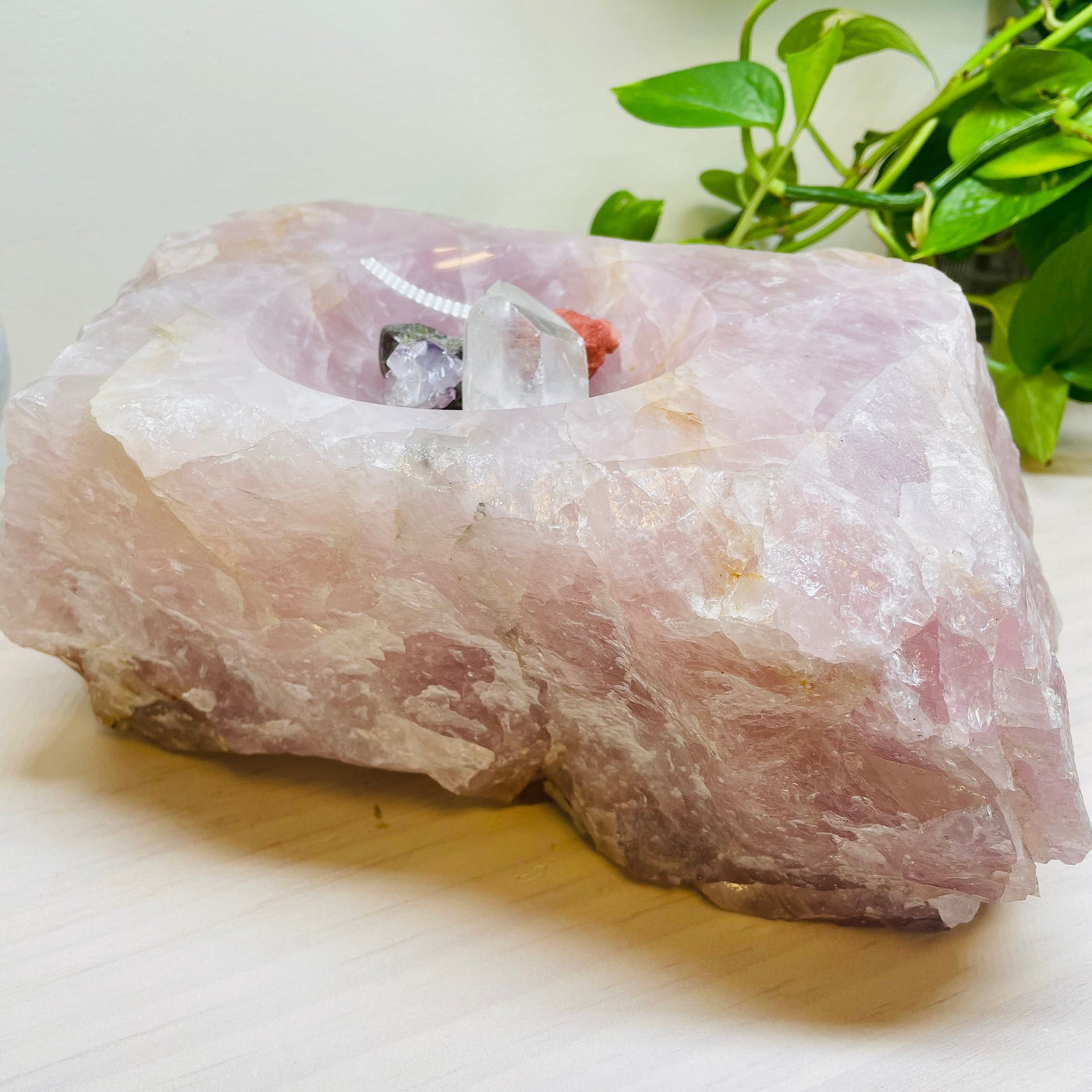 large rose quartz bowl displayed with some crystals to show how deep the bowl part is 