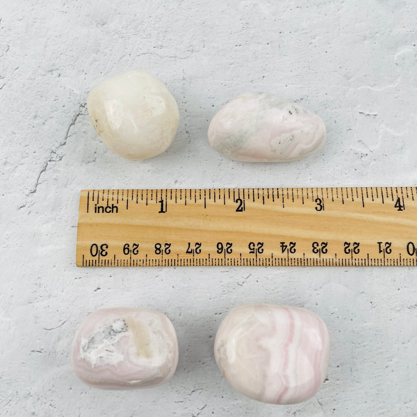 tumbled stones next to a ruler for size reference 