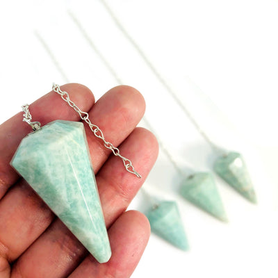 One amazonite pendulum silver being held for size reference.