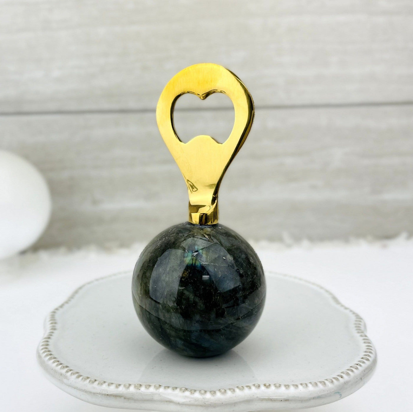 Bottle opener that has a labradorite sphere as the bottom part and a gold opener part.