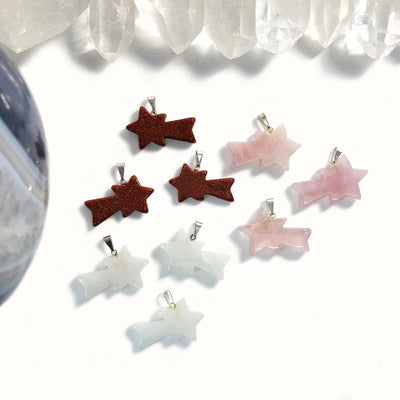 goldstone, crystal quartz, and rose quartz shooting star pendants on display