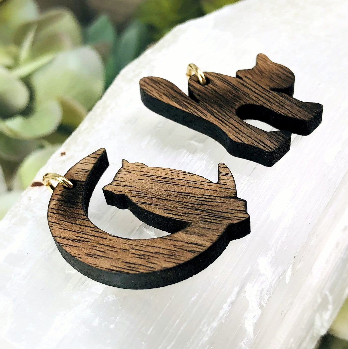 angled shot of 2 wooden cat pendants with decorations