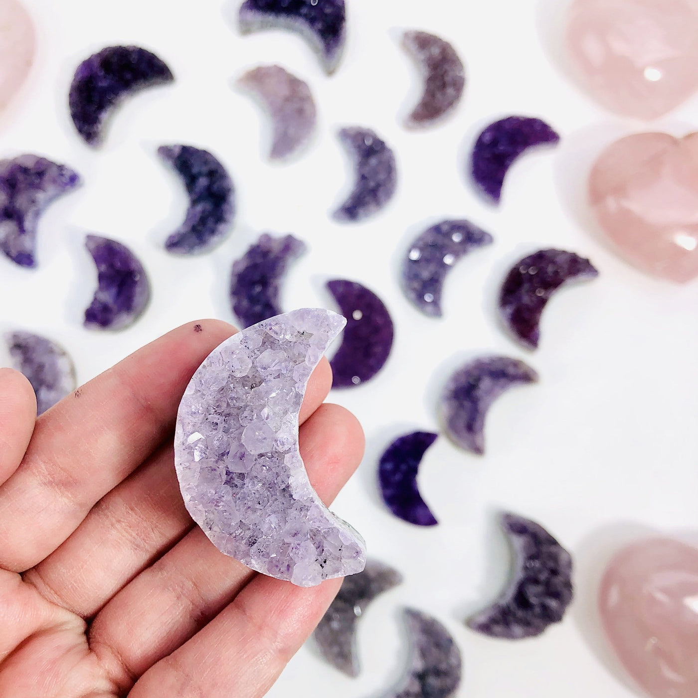 white clear purple amethyst moon in hand to show color tones vary greatly