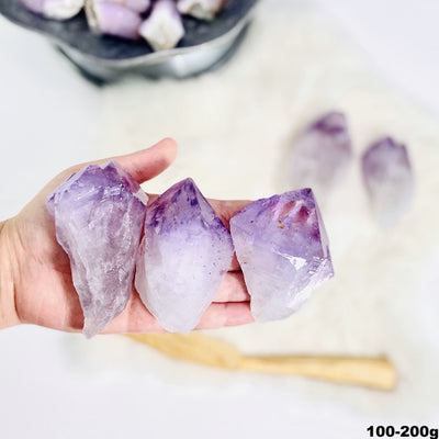 3 large amethyst points in a hand