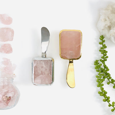 2 Rose Quartz Butter Spreaders next to crystals and plants on white background