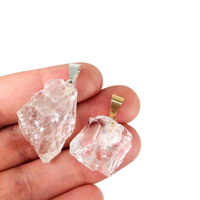 2 crystal quartz pendants with gold and silver bails in hand