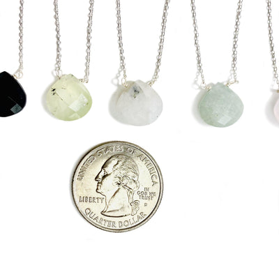 gemstone drop necklace in silver next to quarter for size reference 