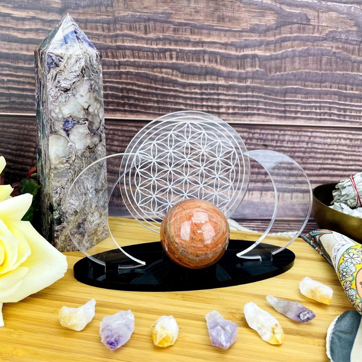 Acrylic Sphere Holder Crescent Moons with Flower of Life holding a sphere within an alter that consists of crystals and flowers.