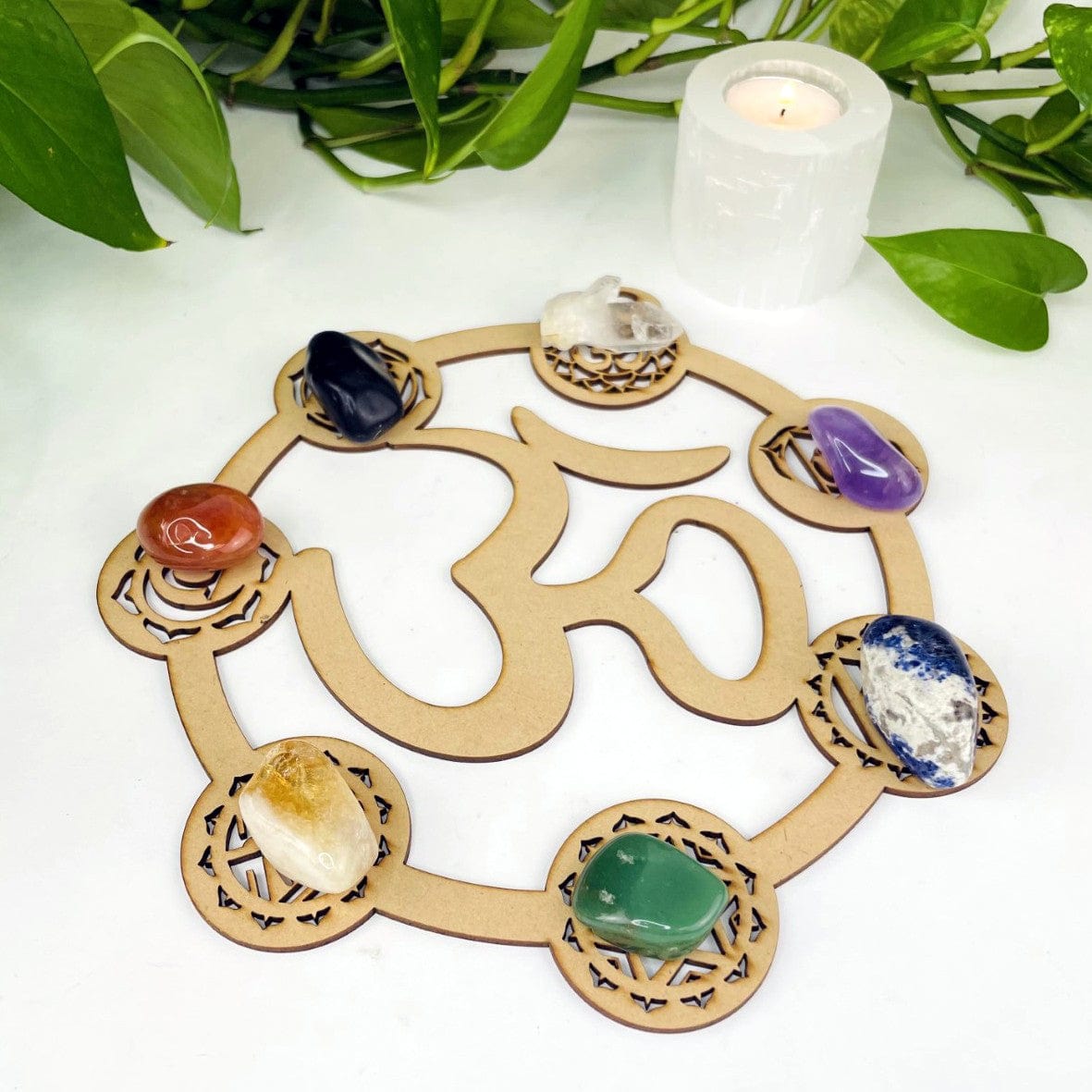 Wood Crystal Grid with seven chakra symbols on edges and OM symbol in the middle on a white background.  Seven chakra stones are placed on the chakra symbols