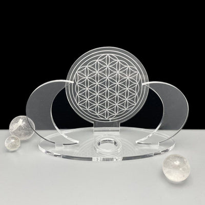 A front facing Acrylic Sphere Holder Crescent Moons - Flower of Life with no sphere within the holder. Surrounded by a few small spheres.