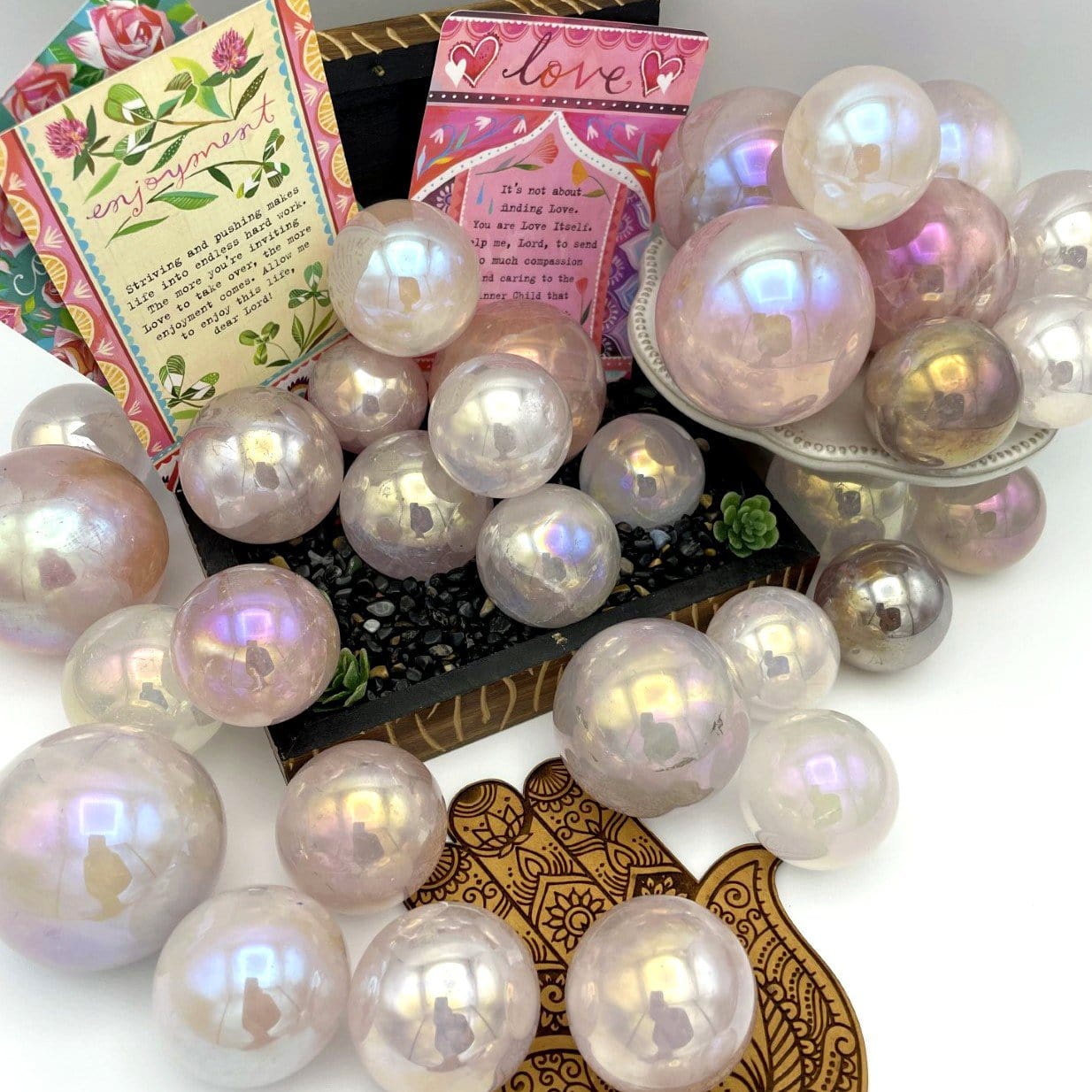 Multiple Rose Quartz Angel Aura Titanium Spheres on a box with other decorations