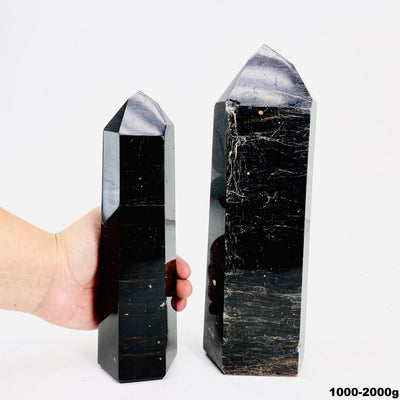 hand behind 1000-2000g black tourmaline with red iron polished points
