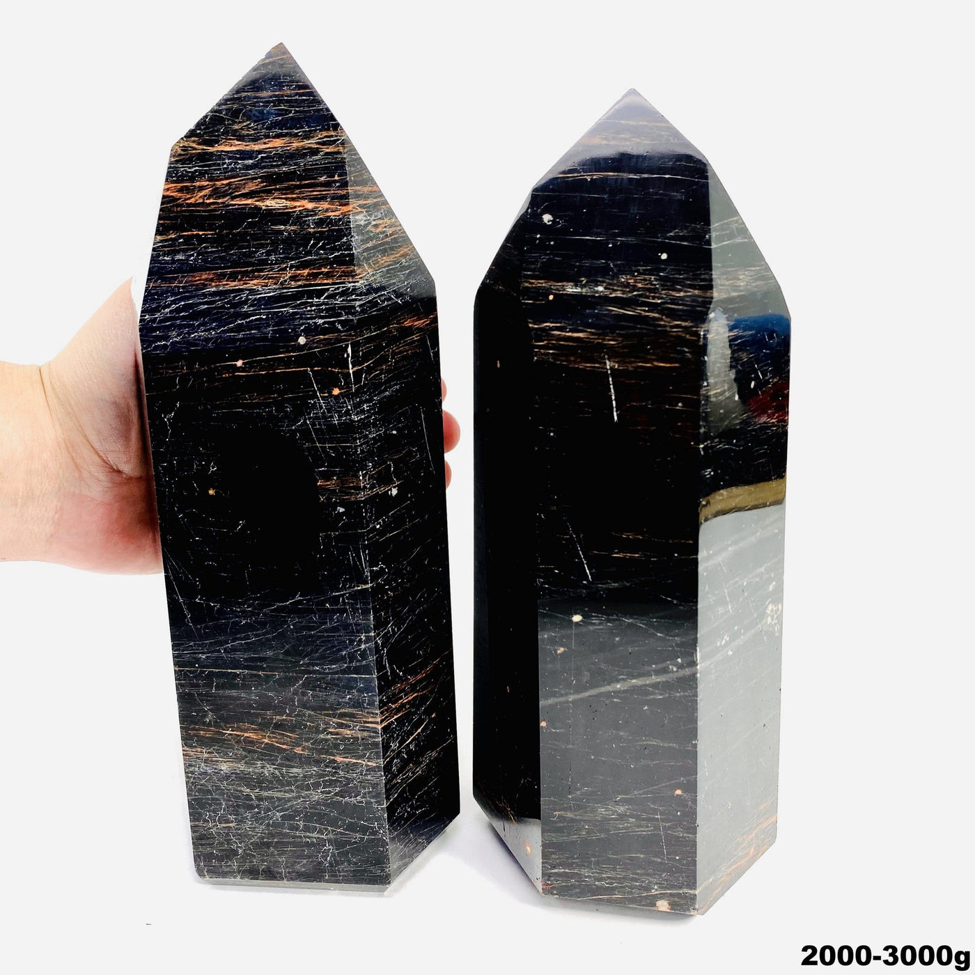 hand behind 2000-3000g black tourmaline with red iron polished points